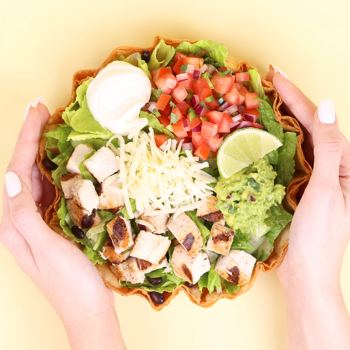 Hands holding tostada salad